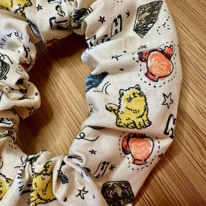 Beige scrunchie with witch patterns (cats, magic potion, books, etc.)